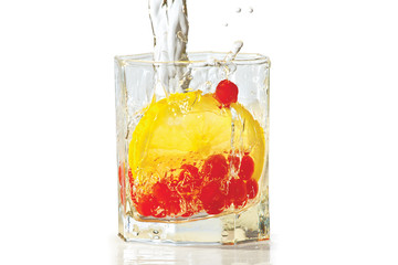 Glass of water, lemon and red cranberries with splash