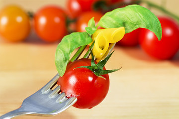 fork with pasta, tomato and basil