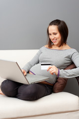 pregnant woman holding laptop and credit card