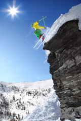 Skier jumping against blue sky from the rock