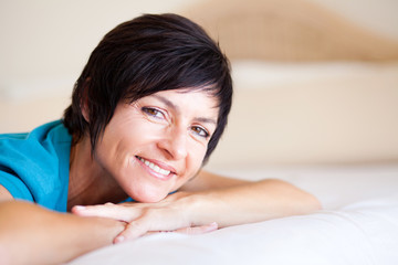 smiling middle aged woman lying on bed relaxing