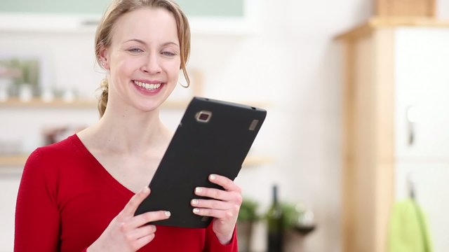 l&auml;chelnde frau mit tablet-computer in der k&uuml;che