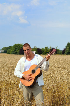Happy young graduate with guitar in the field