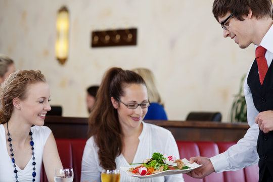 freundlicher kellner serviert einen salat