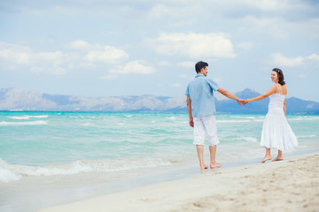 Fototapeta na wymiar Happy young couple walking on a tropical beach