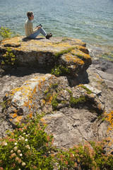 Woman with digital tablet sitting by the lake