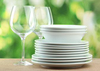 Clean dishes on wooden table on green background