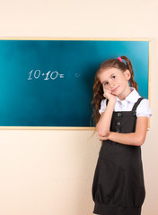 beautiful little girl standing near blackboard in the classroom