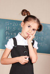 beautiful little girl standing near blackboard in the classroom