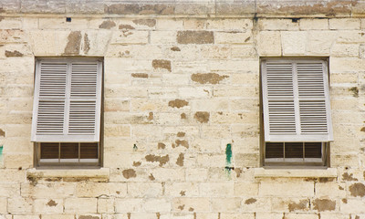 Fototapeta na wymiar Two Wood Shutters in an Old Stone Block Wall