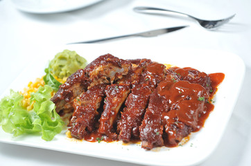 Closeup of barbecued pork ribs and vegetables