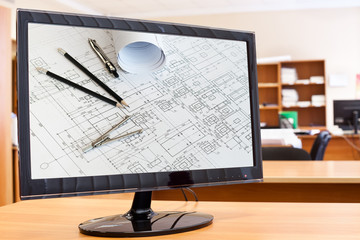 Computer monitor with blueprints and drawing tools on desktop