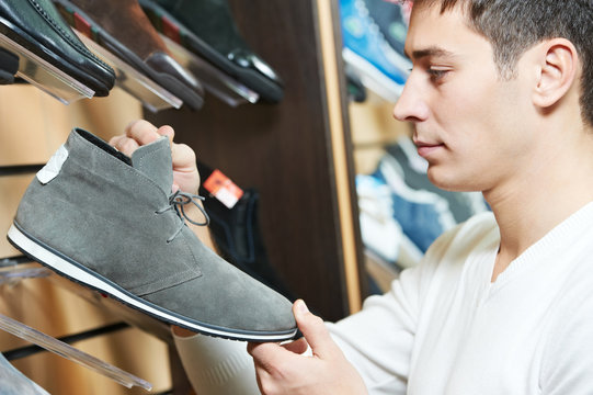 Young Man Choosing Shoe In Clothes Store