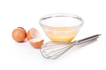 Metal whisk for whipping eggs and eggs in bowl isolated on white