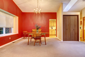 Large dining room with red wall and small wood table.