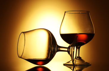 Two glasses of cognac on yellow background