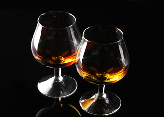 Two glasses of cognac on black background