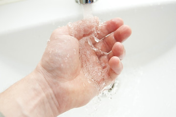 Washing of hands under the crane with water