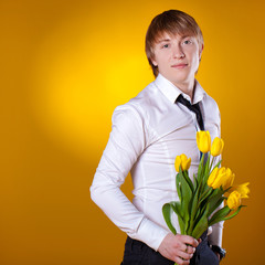 Elegant man holding flowers on yellow