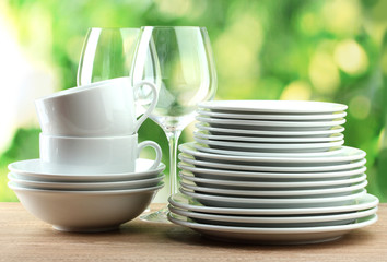 Clean dishes on wooden table on green background