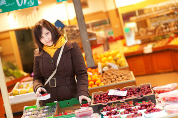 Beautiful young woman buying fruits at market