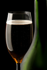 a glass of champagne near a bottle, focus on the glass