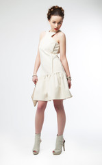 Beautiful fashion model female in light clothes posing on white