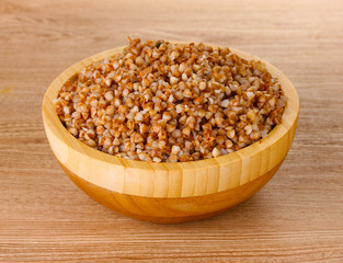 Boiled buckwheat in a wooden bowl on wooden background
