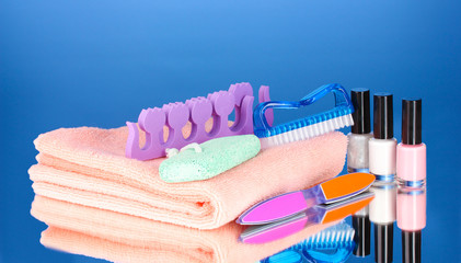 Pedicure set on pink towel on blue background