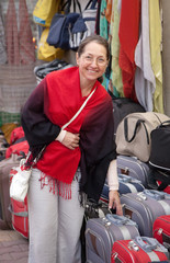 woman chooses suitcase at  shop