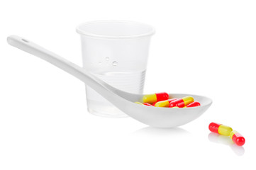 Pharmacy. Antibiotic pills in spoon and plastic glass of water
