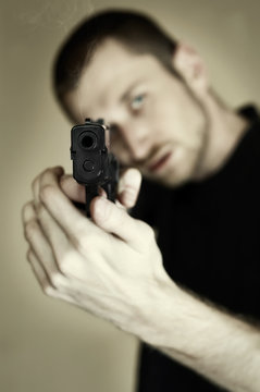 Desaturated image of a man pointing a gun at you