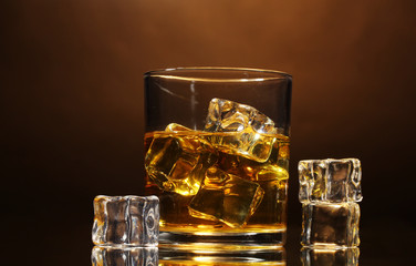glass of whiskey and ice on brown background