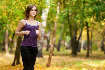 A young girl running in autumn park