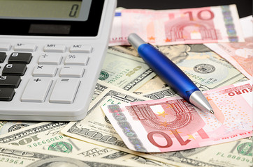 Pen, calculator on banknotes