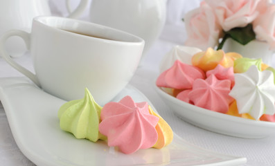 Meringue cookies on a plate with a cup of coffee