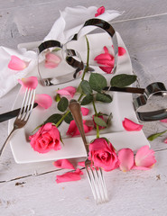 Romantisches Gedeck mit Rosen und Rosenblütenblättern
