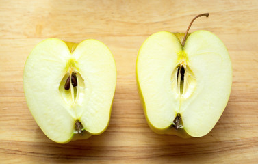 two halves of an apple on a wooden table