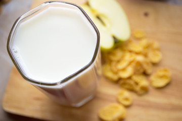 corn flakes with milk and an apple on the table