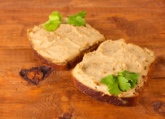 Fresh pate on bread on wooden table