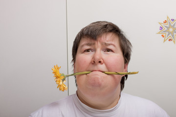 Geistig behinderte Frau hält Blume im Mund