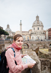 Obraz premium Pretty young female tourist studying a map at the Trajan's forum