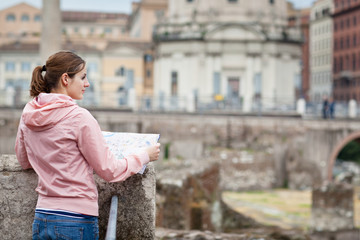 Pretty young female tourist studying a map at the Trajan's forum