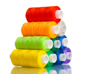 Pyramid of many-coloured bobbins of thread isolated on white
