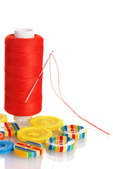 Red bobbin with needle and buttons isolated on white