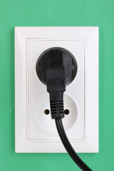 White electric socket with plug on the wall