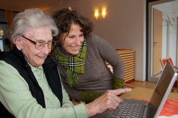 Seniorin am Laptop mit Enkelin