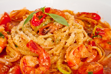 A plate of linguini with sauteed shrimp, tomato, chili  and oliv