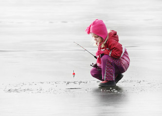 Petit enfant pêchant sur un lac gelé en hiver.