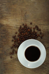 Coffee cup with beans on an old wooden background